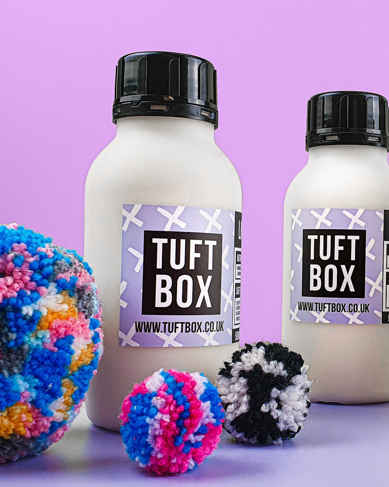 Bottles of liquid latex with colourful pom poms and a lilac backdrop