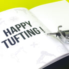 Close up of the Tuftbox AK-I tufting machine manual which reads "HAPPY TUFTING!"