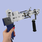 A hand holding the blue AK-I tufting machine with purple background