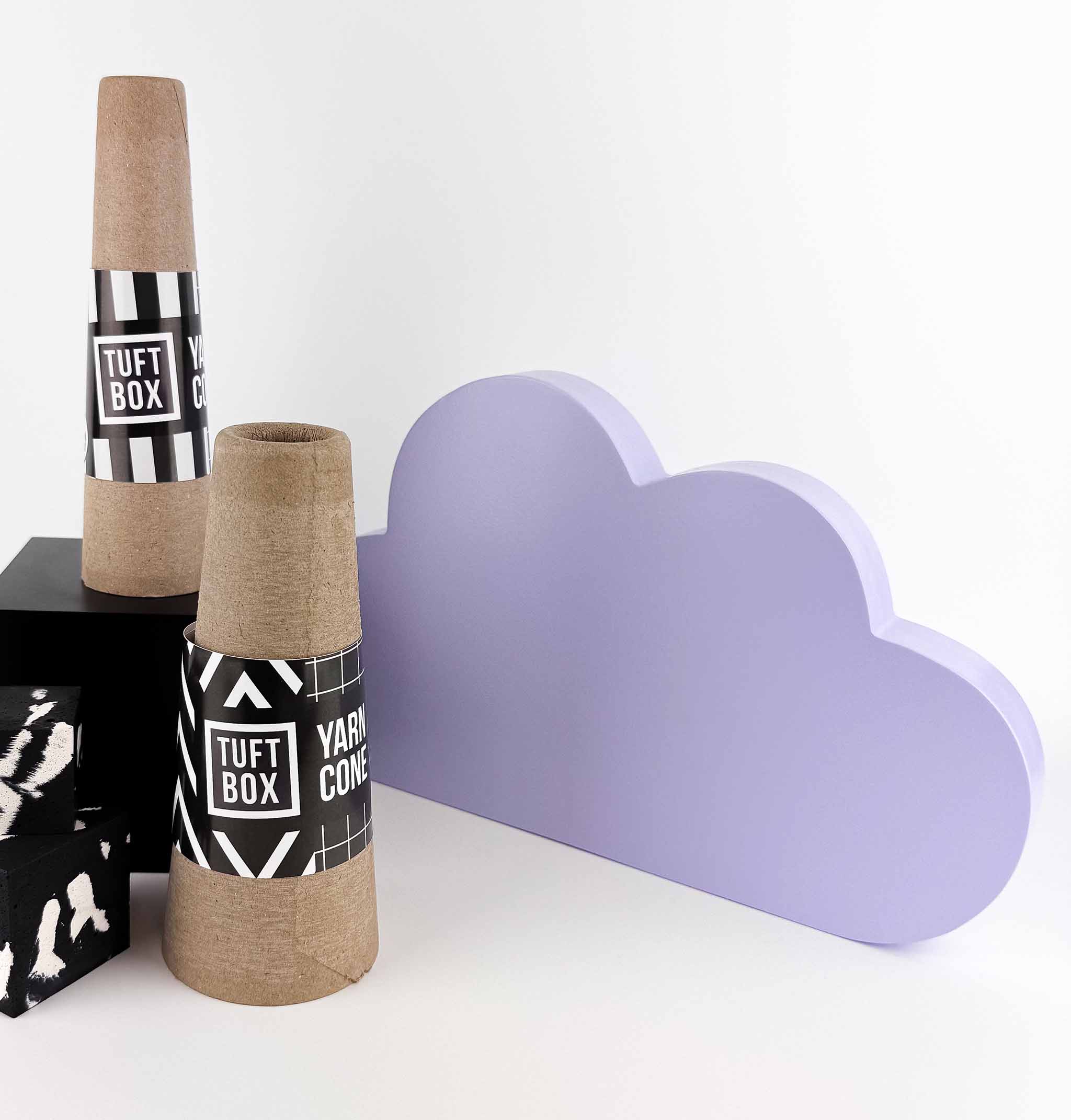 Two cardboard yarn cones with Tuftbox branding on a white background