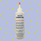 Fabri-Tac Fabric Glue Bottle on Purple Cross Background