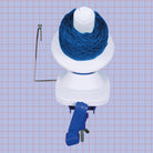 Blue and White KnitPro Yarn Winder with cake of blue yarn on purple grid background