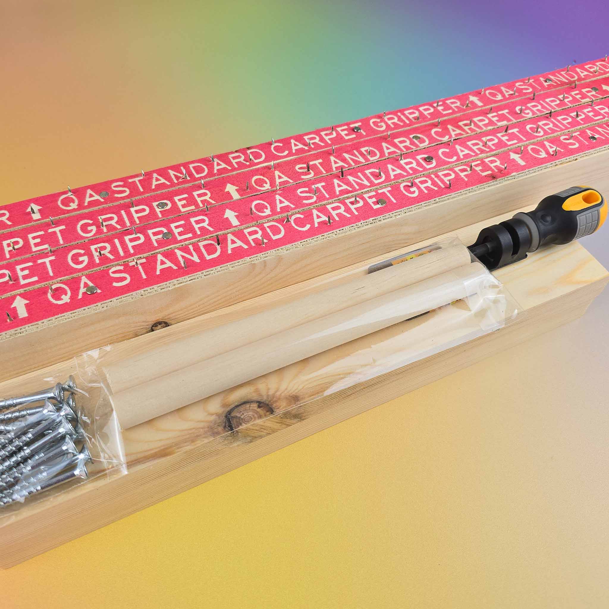 Wooden rug tufting frame and screws and dowels laid out on gradient rainbow background