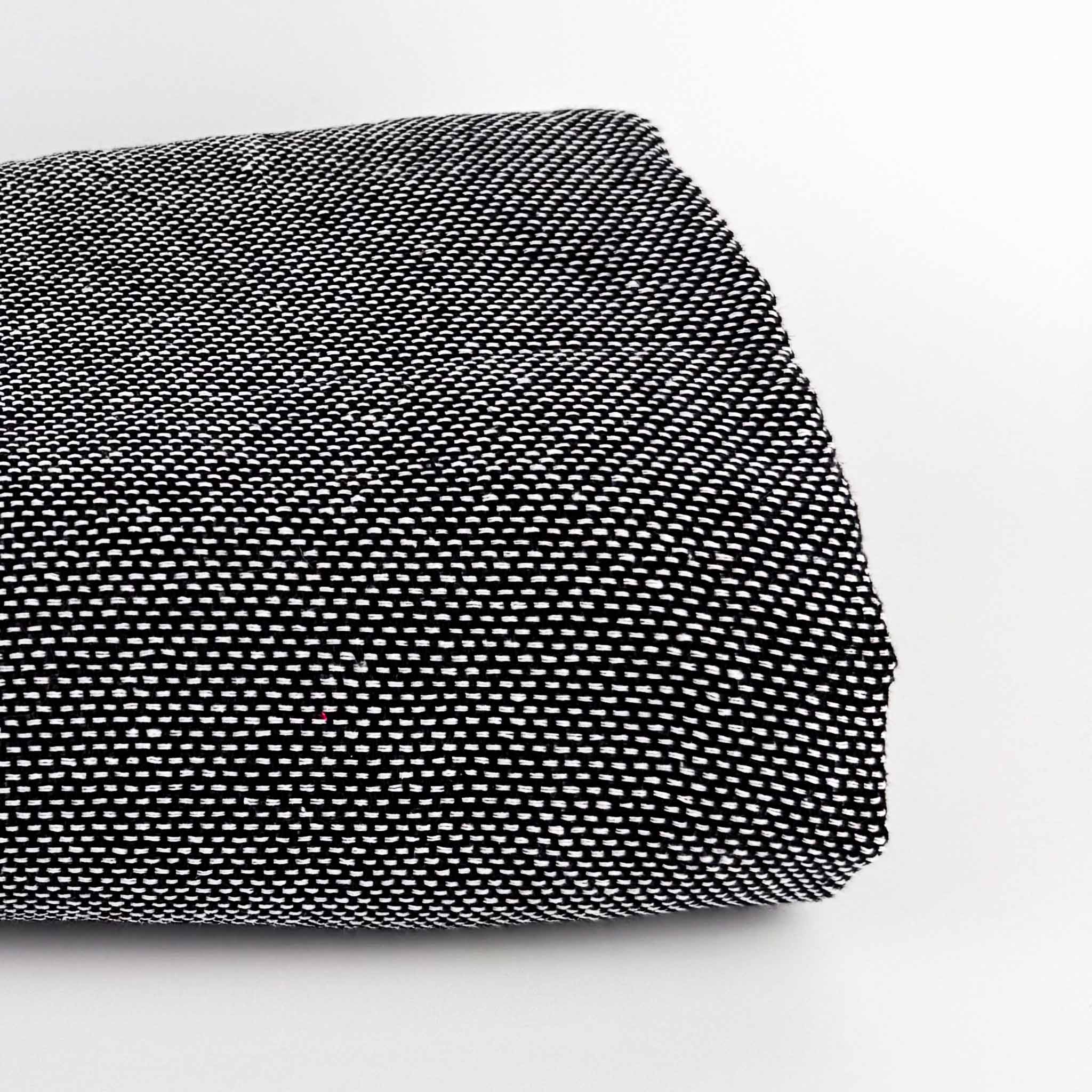 Standard Black and White Woven rug tufting secondary fabric folded in a roll on side with white background