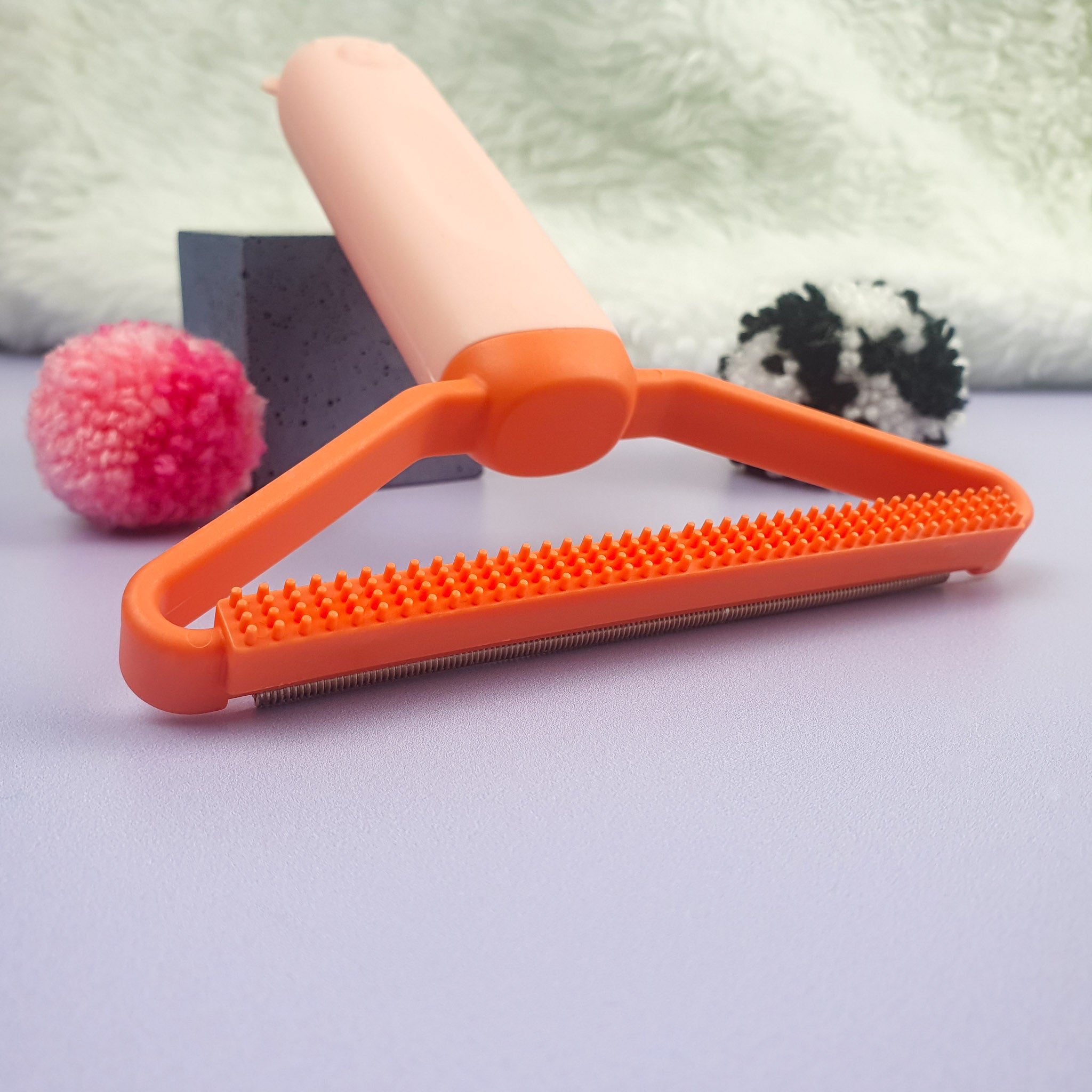 Tufting Fluff Remover Lint Scraper Pink / Orange plastic edge close up