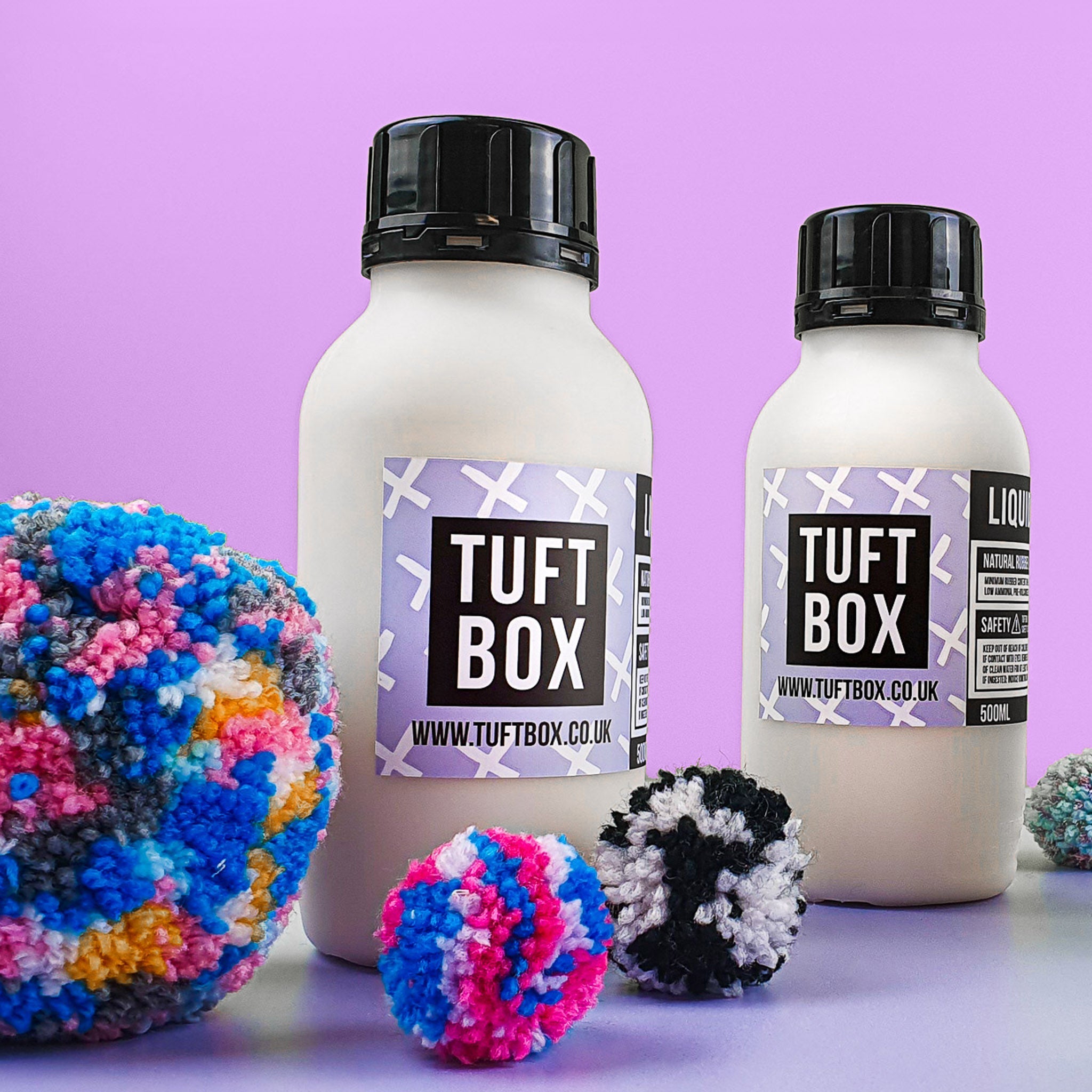 Bottles of liquid latex with colourful pom poms and a lilac backdrop