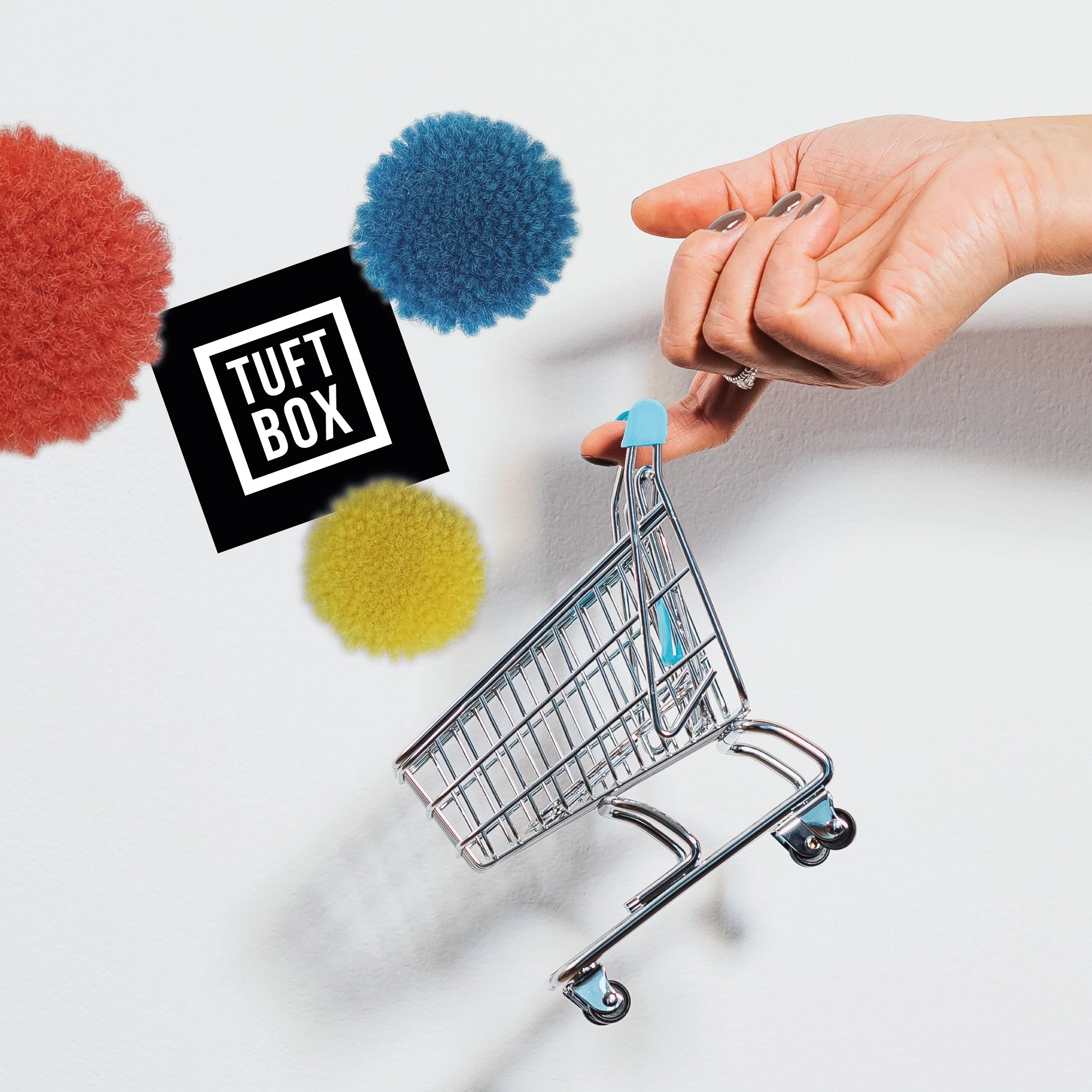 A mini shopping cart being filled with fluffy pompoms