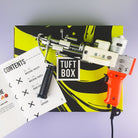Orange AK-I tufting machine on top of box with the Tuftbox instruction manual 