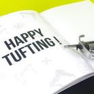 Close up of the Tuftbox AK-I tufting machine manual which reads "HAPPY TUFTING!" 