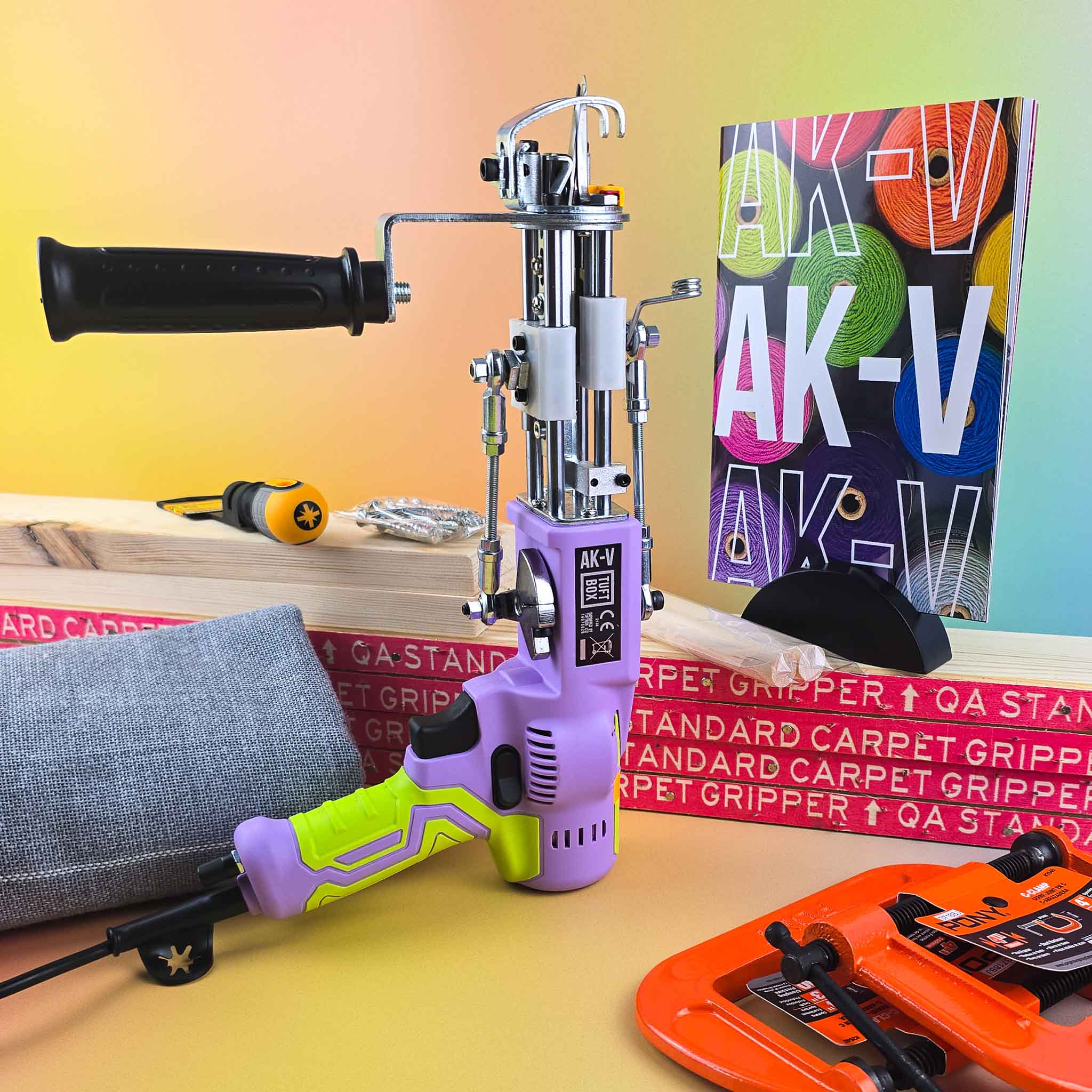 Purple AK5 AK-V rug tufting machine with rug tufting kit components including frame, fabric and instruction booklet on soft gradient rainbow background