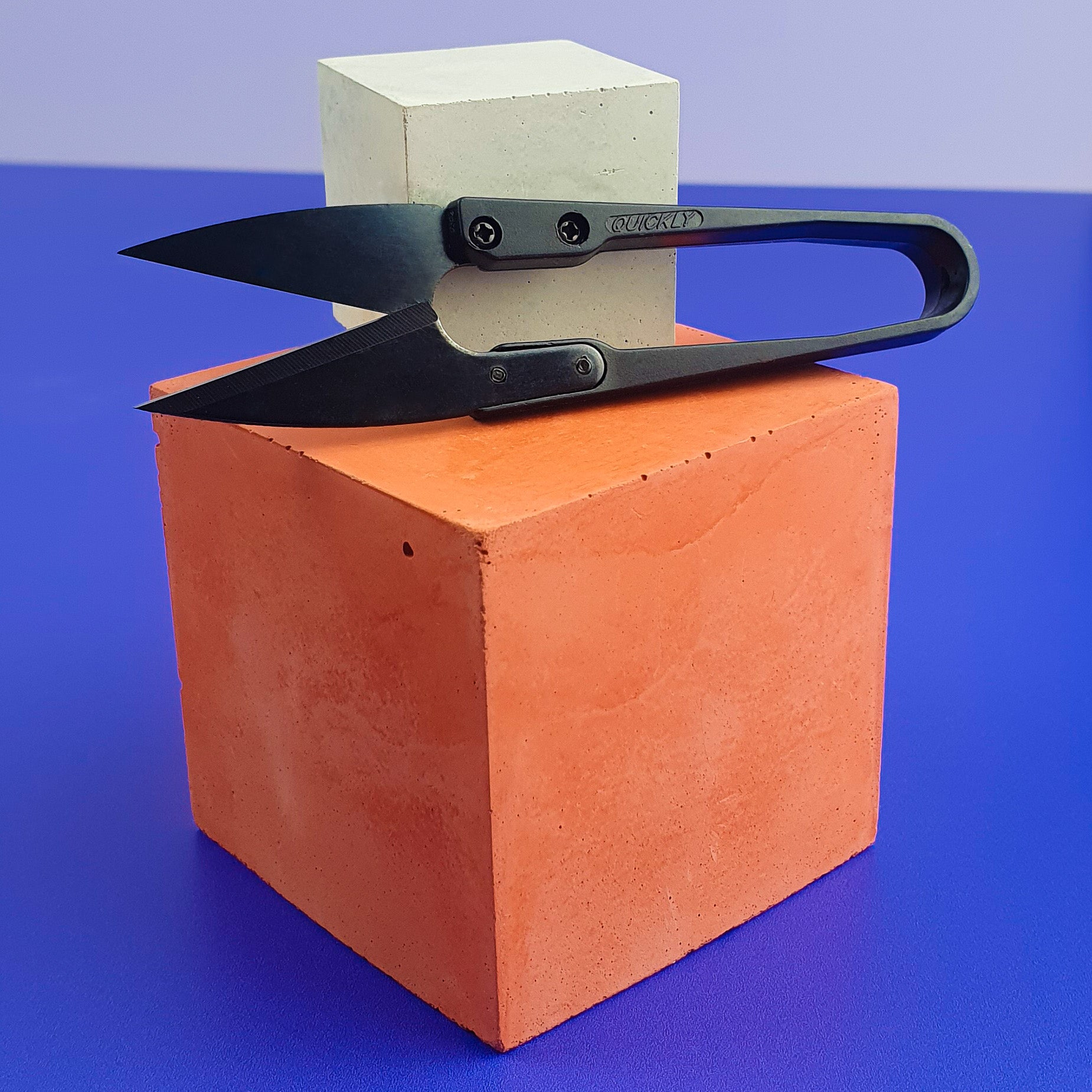 Black Thread Cutters resting on mini concrete orange and grey cubes