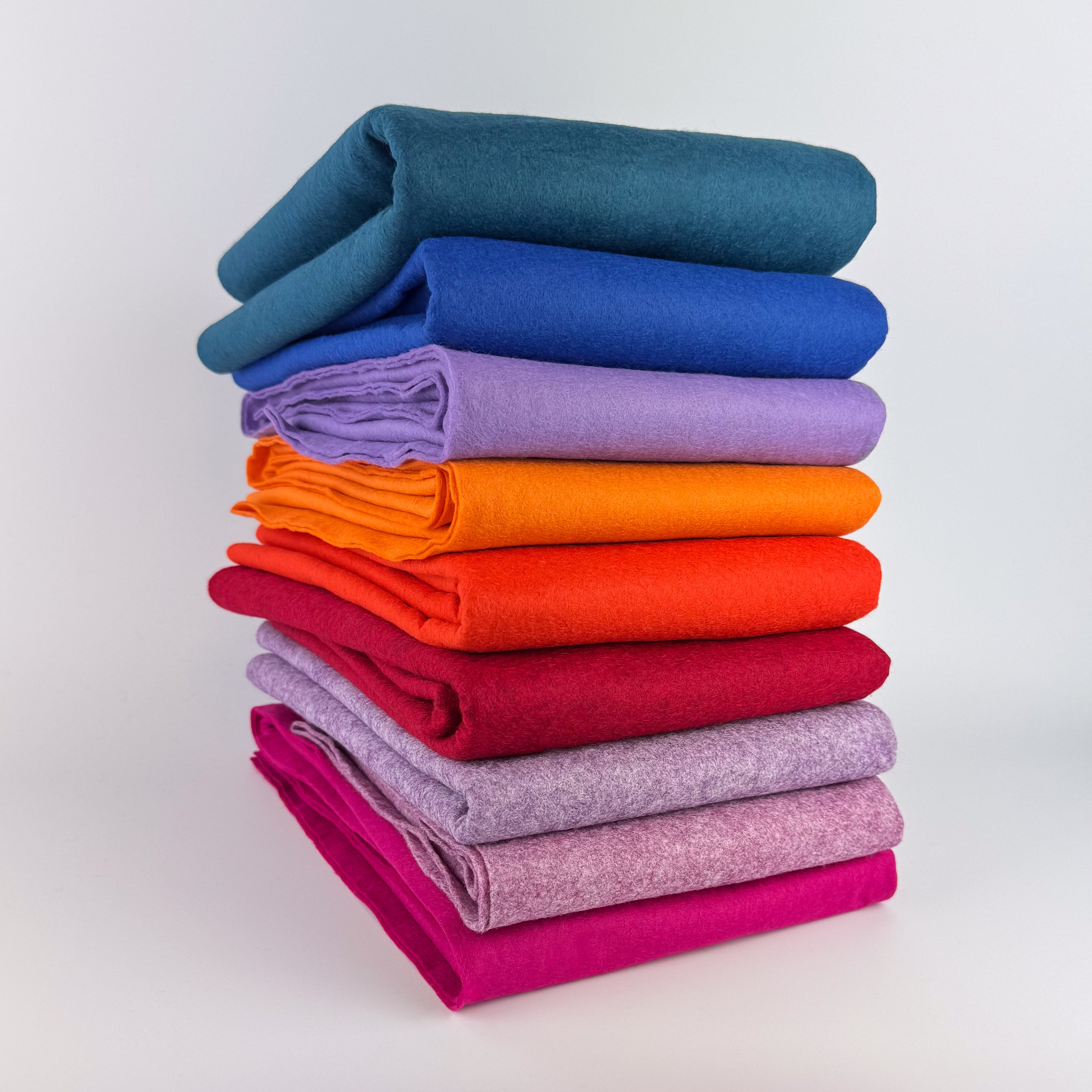 Stack of folded colorful felt backing fabrics on a white background