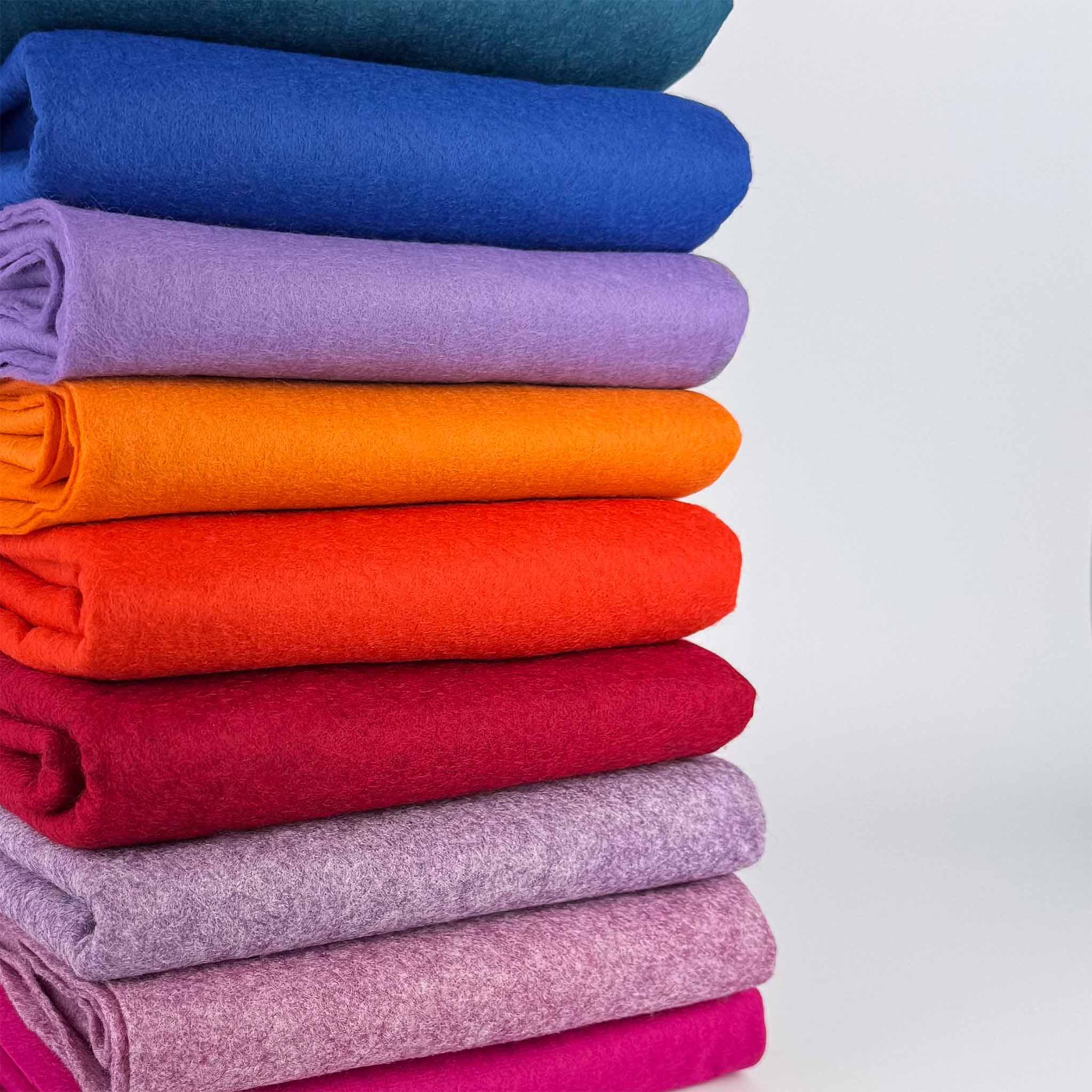 Stack of colorful folded felt backing secondary fabric on a white background