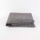Folded gray non slip tufting fabric with a pattern on a white background