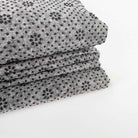 Stack of gray non slip tufting fabric with black bead silicone pattern on a white background