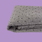 Folded gray non slip tufting fabric with black bead silicone pattern on a purple background