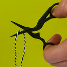 Black Crane Embroidery Scissors in action cutting a black/white thread
